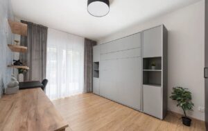 główna sypialnia połączona z pokojem do pracy zdalnej nowoczesne 4 pokojowe mieszkanie na sprzedaż w stylu skandynawskim drewno, biel, przytulne wnętrze, tapety widok na sypialnie gabinet